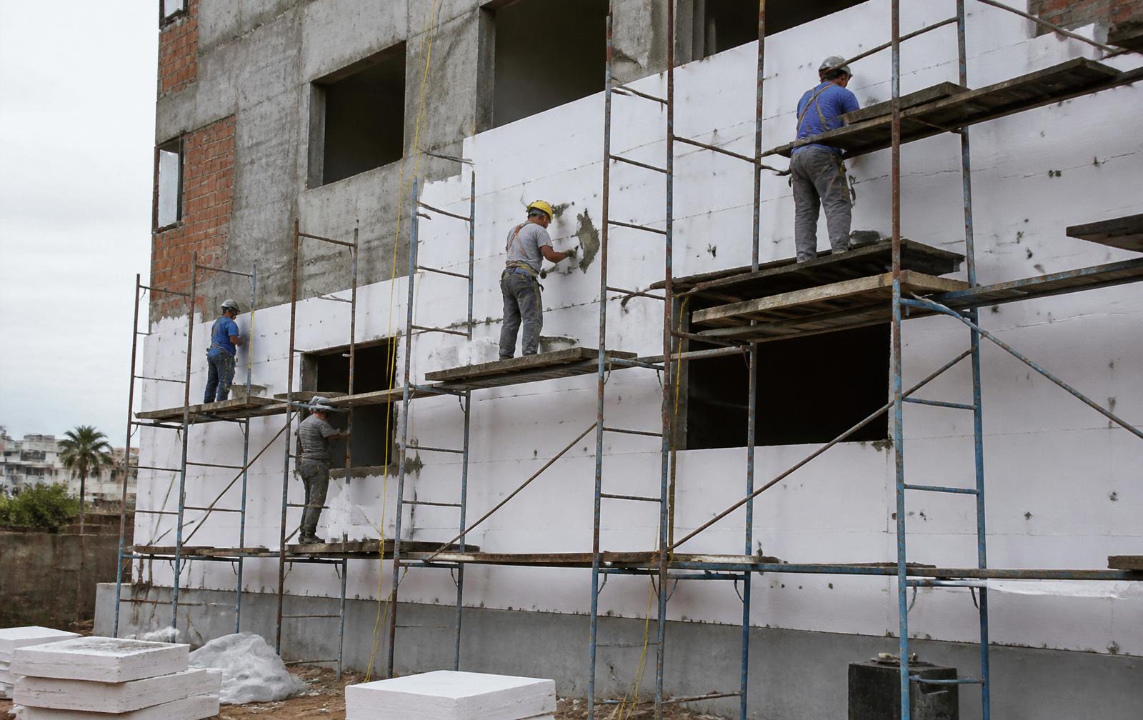Trabalhadores aplicando placas de EPS em revestimento externo de fachada